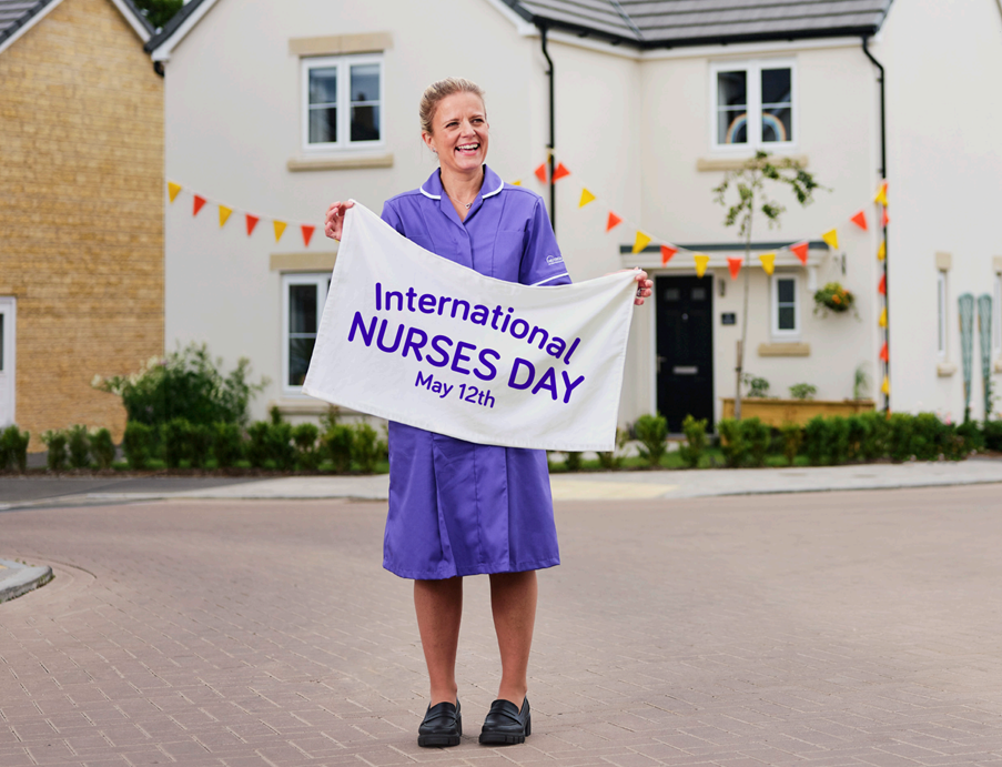 Nurse smiling and holding an International Nurses Day banner